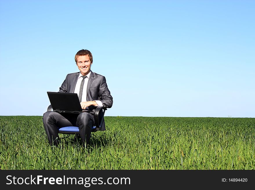 Happy businessman on field, with a laptop