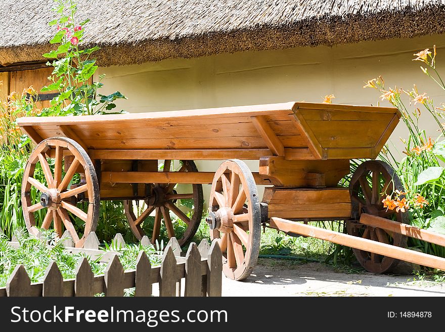 Cart is wooden near the shed of covered a straw