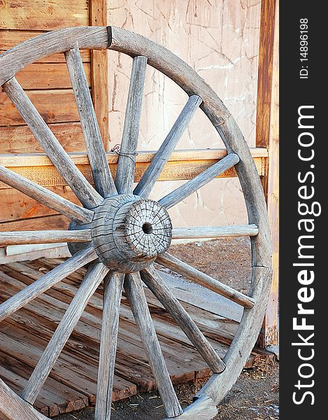 Old weathered wagon wheel leaning against fence. Old weathered wagon wheel leaning against fence
