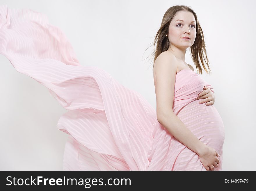 Young pregnant woman and pink flowing textile on white background. Young pregnant woman and pink flowing textile on white background.