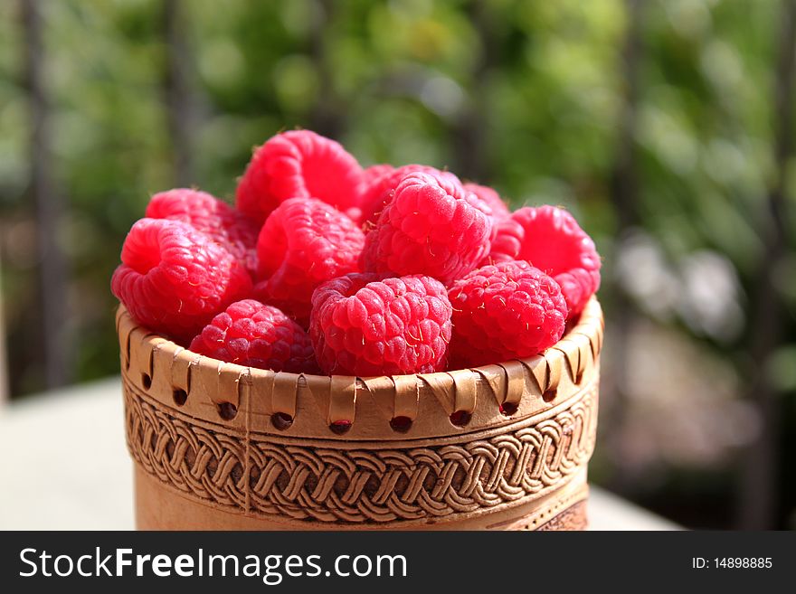 Close up view of raspberries in a wodden decorative bowl. Close up view of raspberries in a wodden decorative bowl