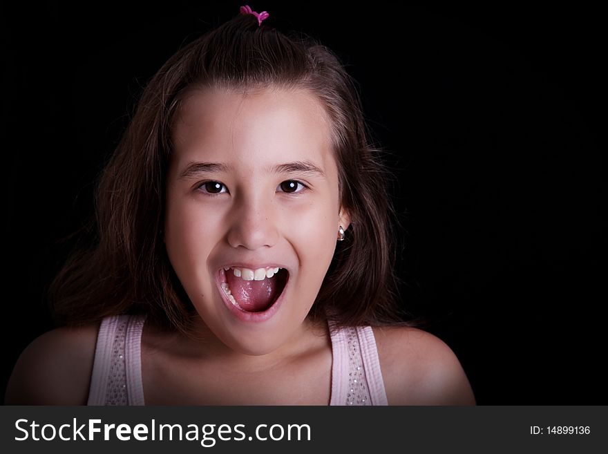 Girl screaming on a black background. Ten years old
