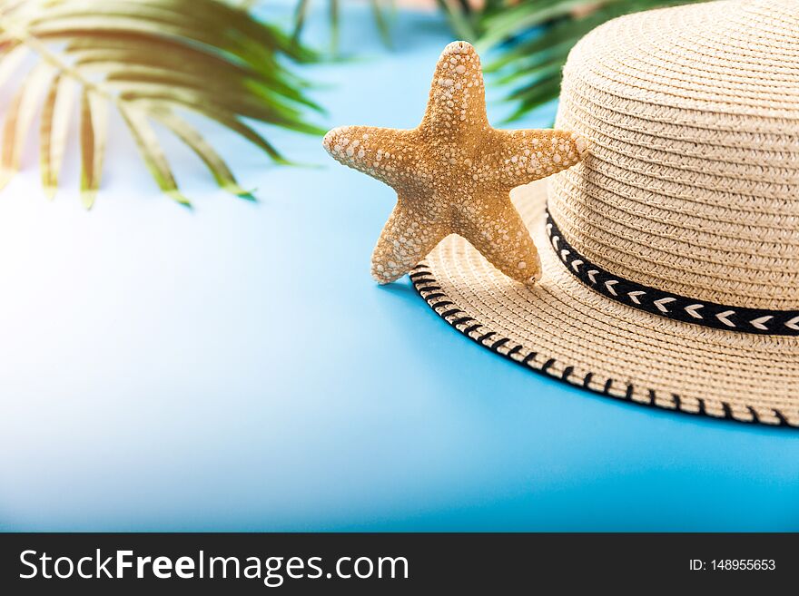 Summer holiday background. Beach accessories: starfish, tropical palm leaves, straw hat on blue background. Vacation and travel items. Summer concept. Front view. Summer holiday background. Beach accessories: starfish, tropical palm leaves, straw hat on blue background. Vacation and travel items. Summer concept. Front view