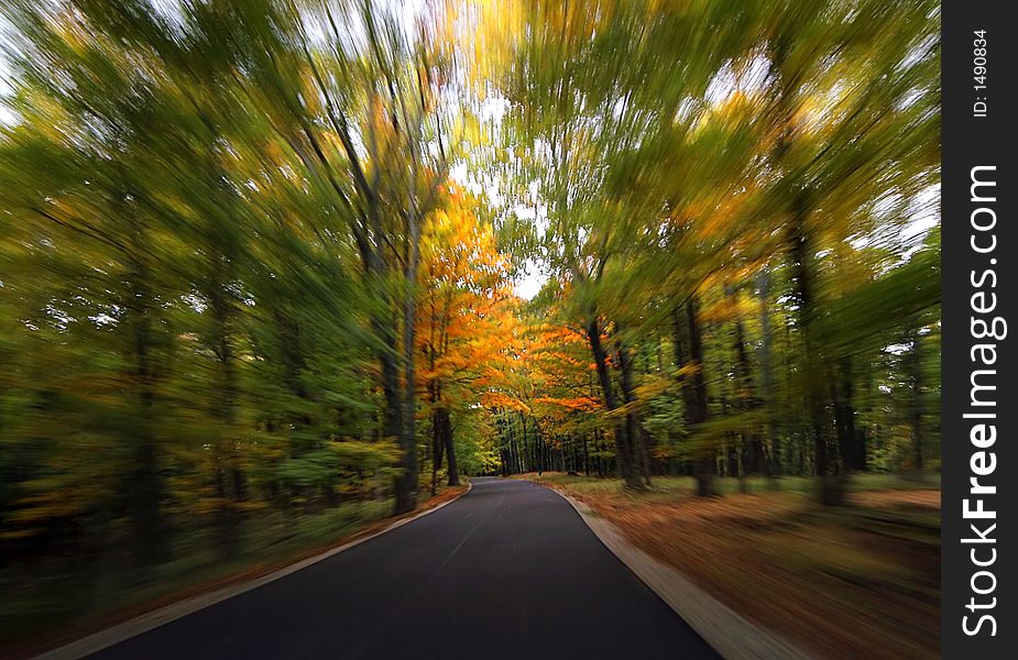 Driving along a blacktop road during the fall with motion blur. Driving along a blacktop road during the fall with motion blur
