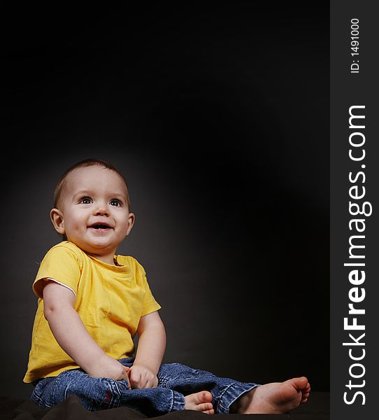 Beautiful baby boy poses on a black background