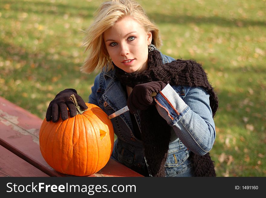 Beautiful young woman carving a pumpkin. Beautiful young woman carving a pumpkin.
