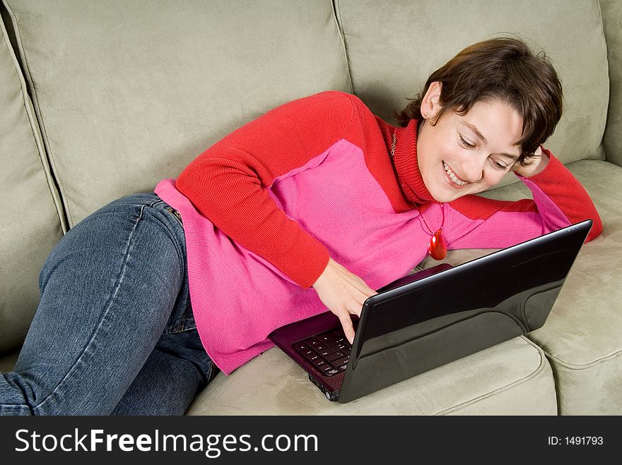 Woman smiling on couch with a laptop. Woman smiling on couch with a laptop