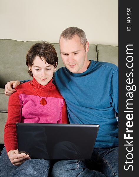 Pair leaning against the couch with laptop. Pair leaning against the couch with laptop