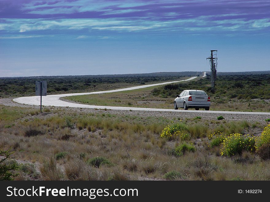 A lonely car on a road stretching towards the horizon. A lonely car on a road stretching towards the horizon