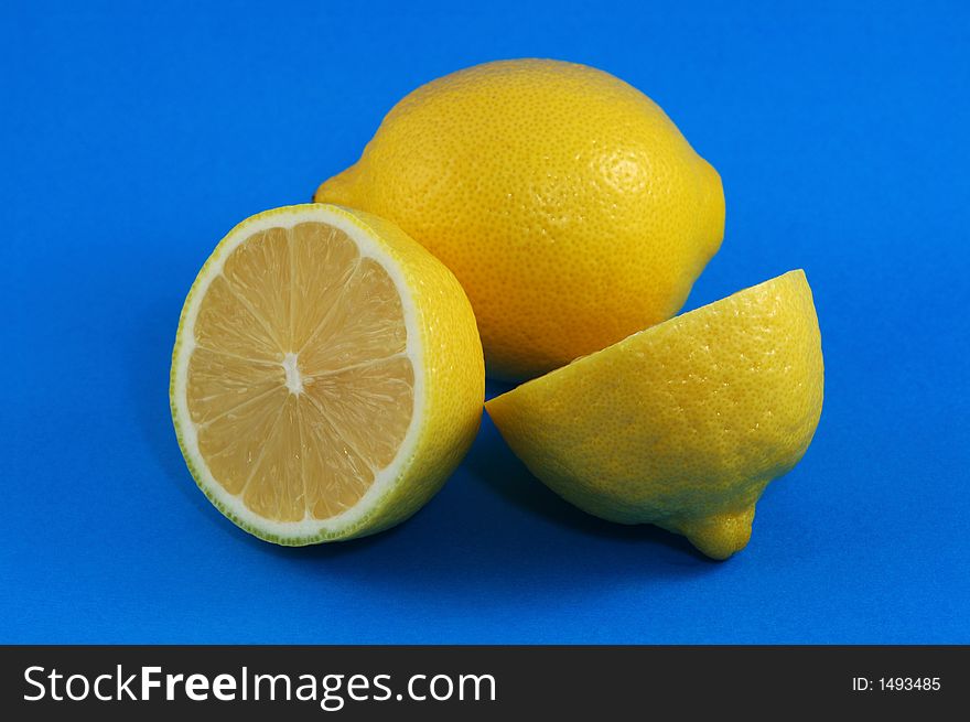Whole and Cutted Lemons Over Blue Background. Whole and Cutted Lemons Over Blue Background