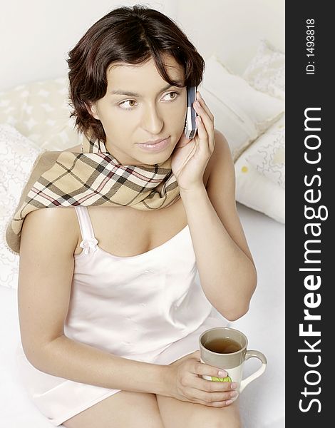 Young woman, girl with a sore throat, drinking tea and making a phonecall. Young woman, girl with a sore throat, drinking tea and making a phonecall