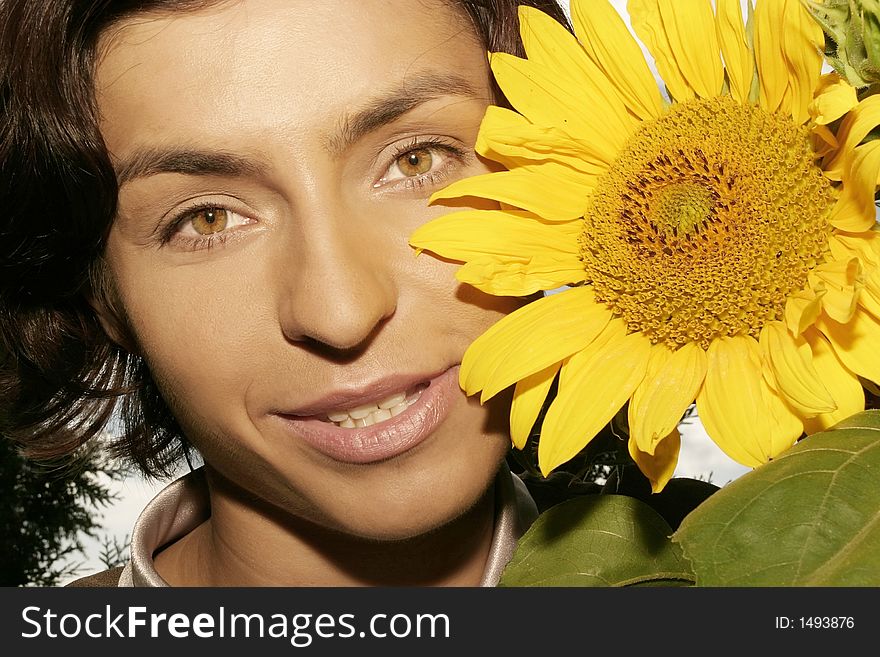 Portrait of a young woman, brunette with a sunflower-close up