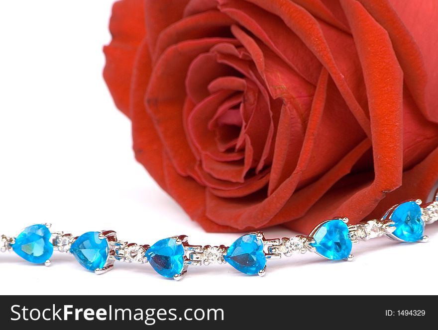 Beautiful red rose with blue color jewelery on it, ISOLATED on white. Beautiful red rose with blue color jewelery on it, ISOLATED on white