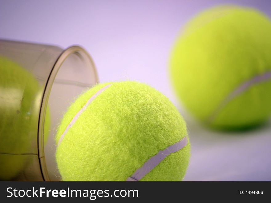 Three tennis balls emerging from the tube they are stored in