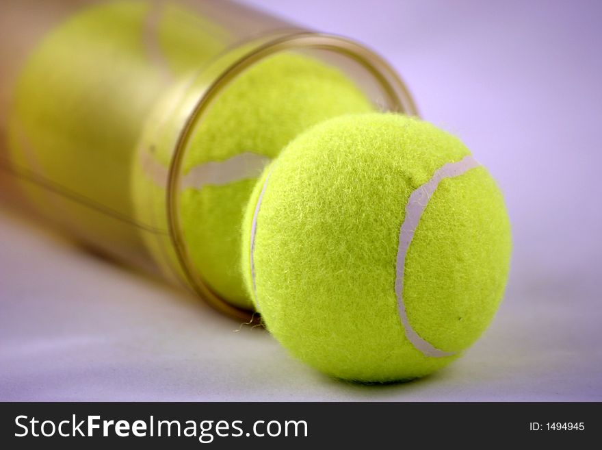 Three tennis balls emerging from the tube they are stored in