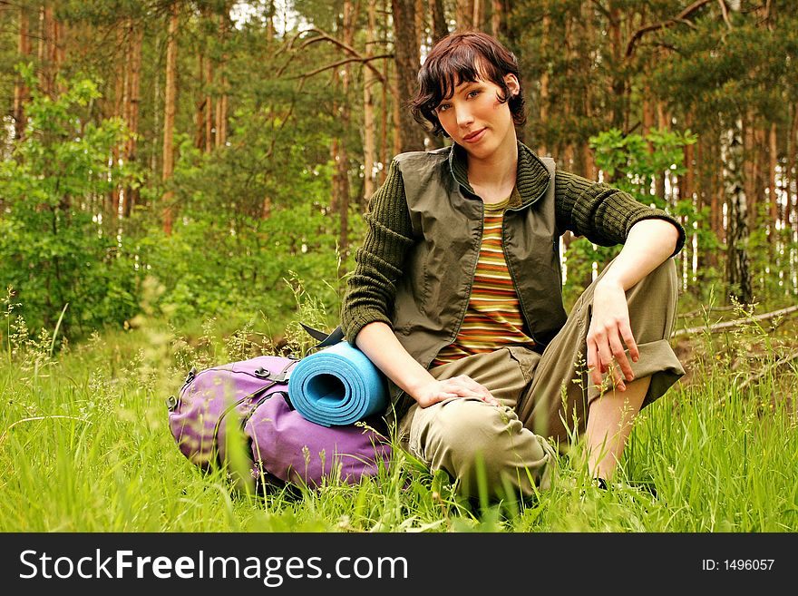 Girl, young woman with a backpack hiking in a forest-resting
