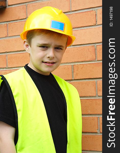 Boy playing workman in safety vest and hard hat