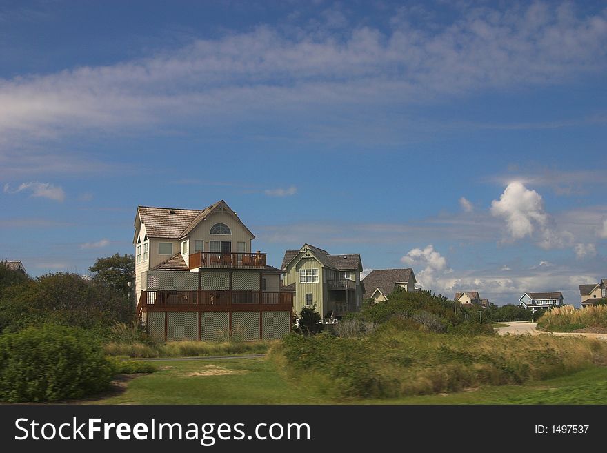 Beach homes on the coast amongst the green grass and blue skies. Beach homes on the coast amongst the green grass and blue skies