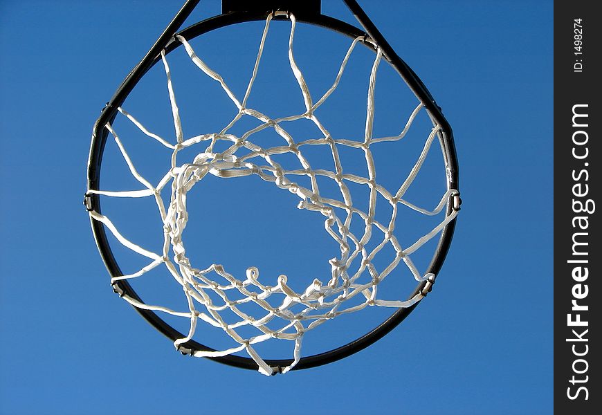 Shot of a basketball rim and net taken against the bright blue sky, looking up. Shot of a basketball rim and net taken against the bright blue sky, looking up.