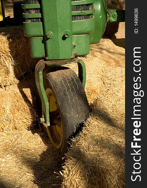 Close-up of the front of a green tractor stuck in bales of hay.