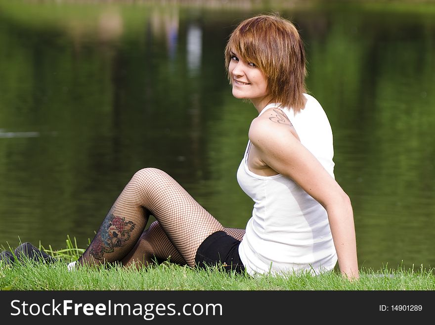 Beautiful girl sits on the bank of lake
