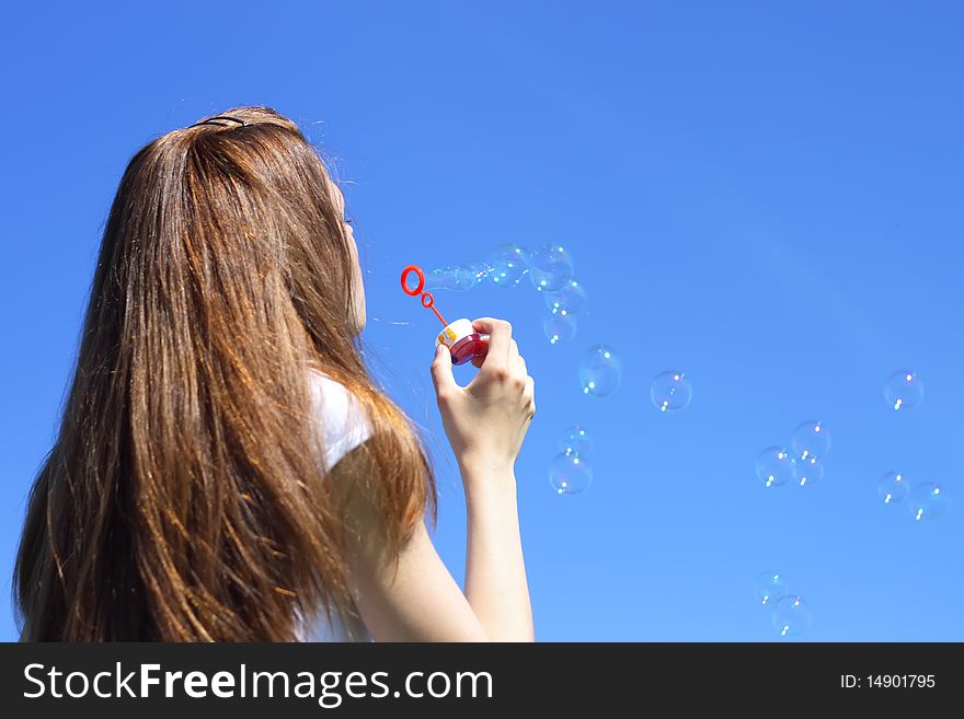 Girl blowing bubbles on a blue background