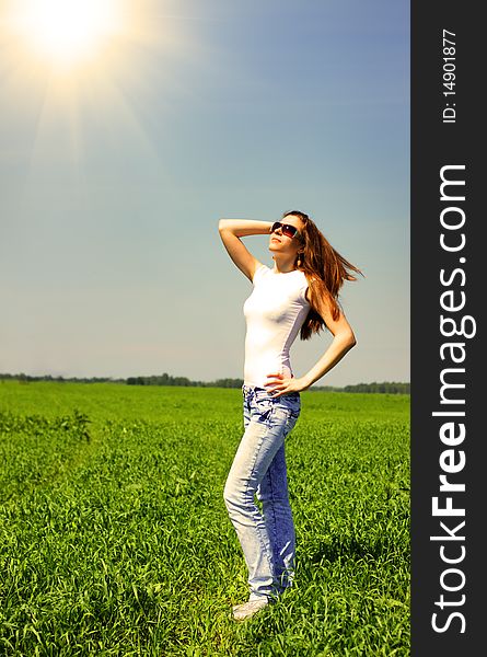 Girl stands on the field and looks at the sun