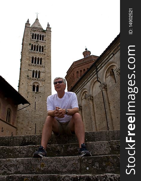 Mature male tourist sitting on steps infront of an historic Italian church. Mature male tourist sitting on steps infront of an historic Italian church.