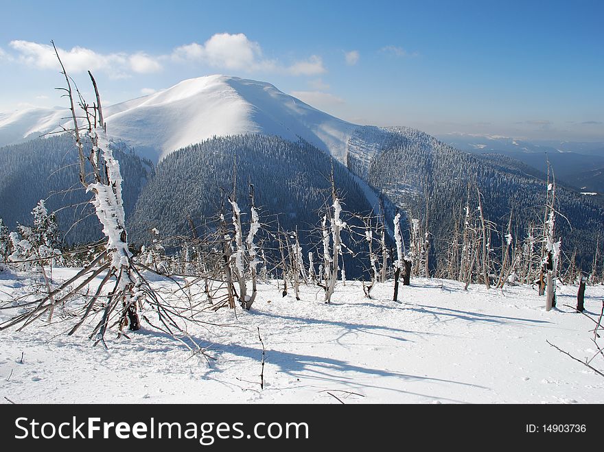 White mountain with the dark blue sky in a winter landscape with a snow hillside. White mountain with the dark blue sky in a winter landscape with a snow hillside.