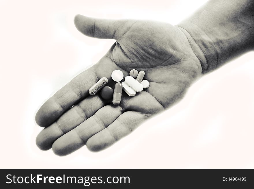 Hand in black and white holding pills isolated on white. Hand in black and white holding pills isolated on white