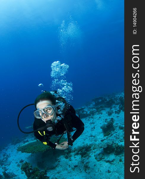 Woman scuba diver swims in clear blue water
