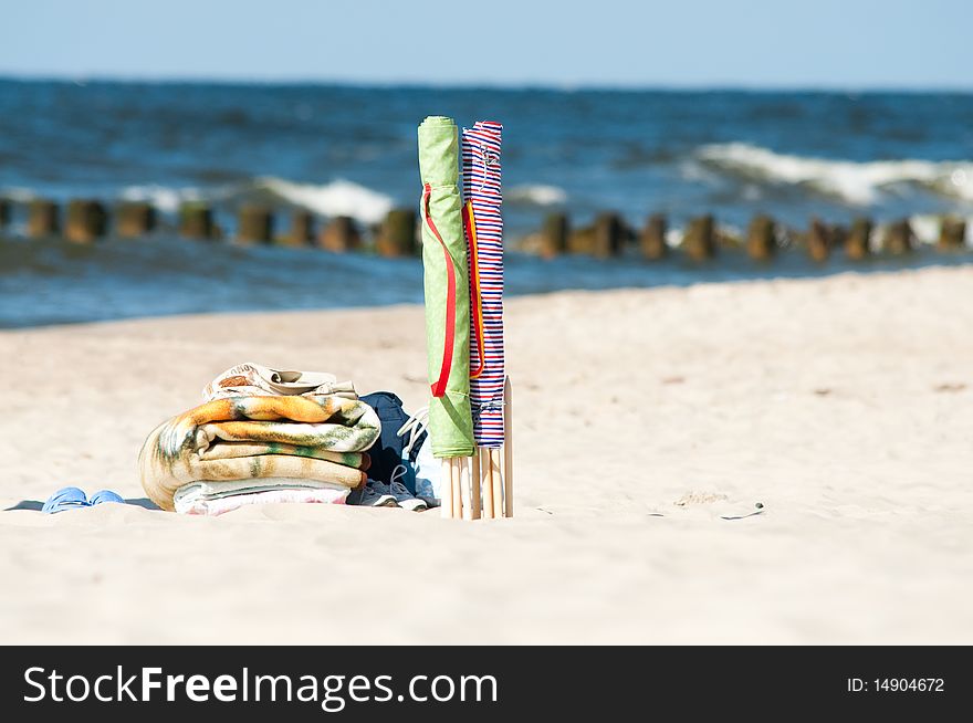 Colorful textile beach windbreak stuck in sand and towels. Colorful textile beach windbreak stuck in sand and towels