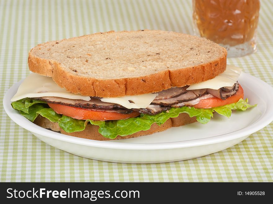 Roast beef sandwich on rye bread with swiss cheese, tomato and lettuce