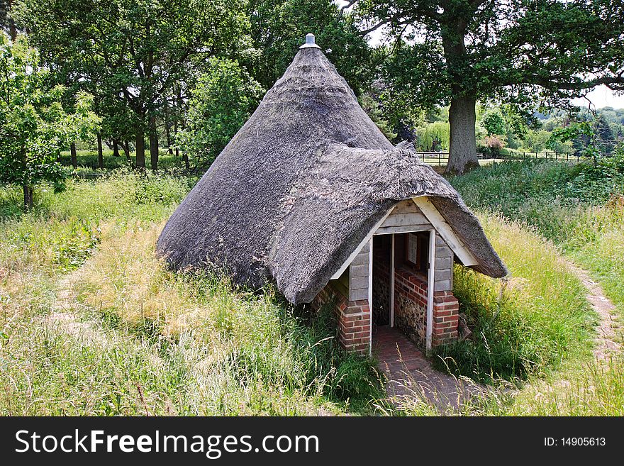 Thatched Ice House set amongst the trees in an English landscape
