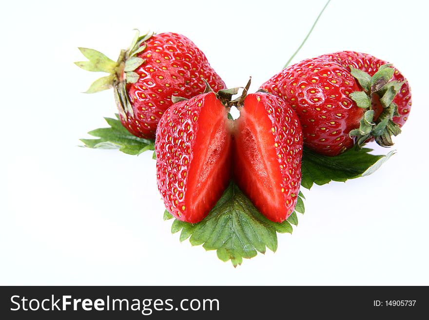 Strawberries on a leaf, one cut in half, on white background