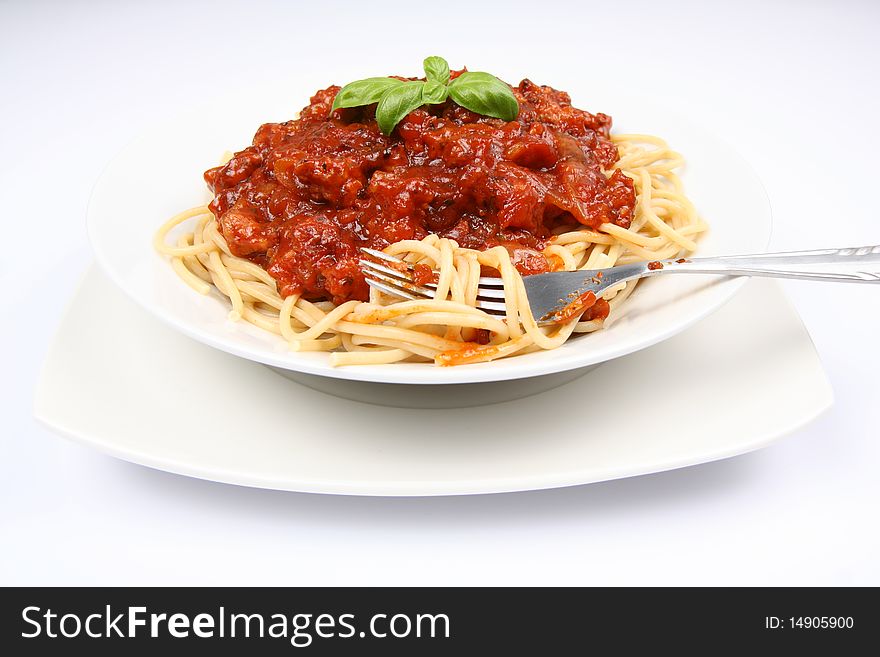 Spaghetti bolognese on a plate and a fork decorated with basil