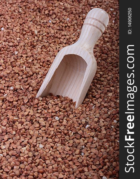 Buckwheat groats with a wooden deep spoon for packaging.