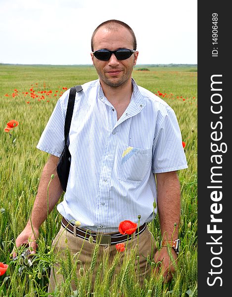 A young man with glasses standing in a field of wheat. A young man with glasses standing in a field of wheat