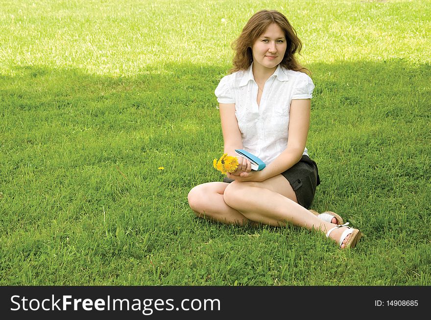 Atrractive woman is sitting on grass with book. Atrractive woman is sitting on grass with book