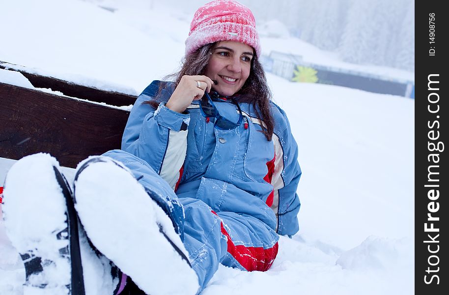 Portrait of a young woman, sitting on a bench in winter, resting a little bit after skiing. Portrait of a young woman, sitting on a bench in winter, resting a little bit after skiing