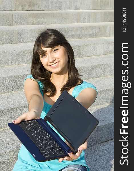 Woman outdoors sitting on the steps the school with a laptop. Notebook in hand stretched out in the frame. Woman outdoors sitting on the steps the school with a laptop. Notebook in hand stretched out in the frame