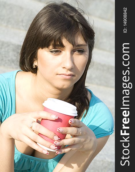 A beautiful young woman relaxing. Drinking coffee from paper cups. Portrait. A beautiful young woman relaxing. Drinking coffee from paper cups. Portrait