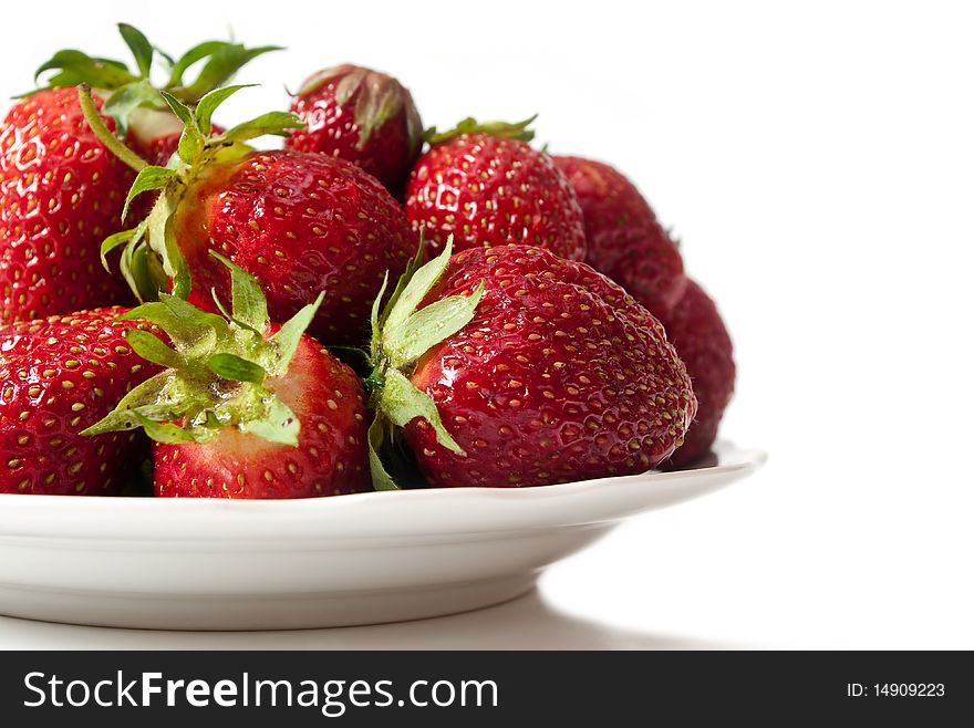 Ripe strawberry on a dish, with a shade, on a white background