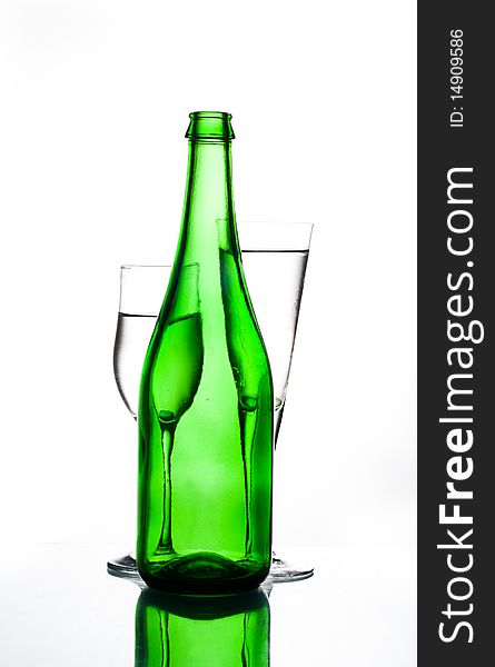 Green bottle and two glasses on glass table water