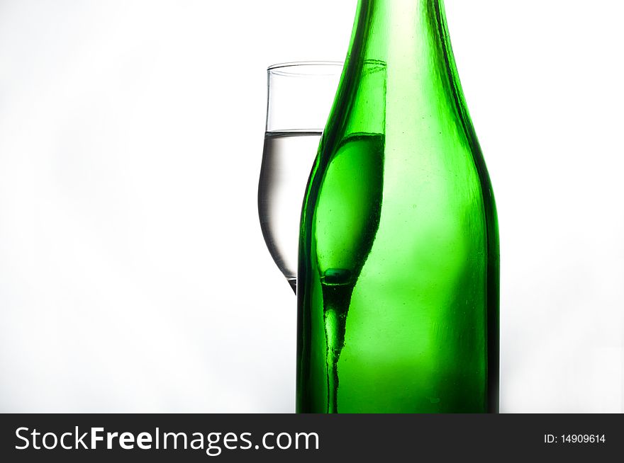 Green bottle and glasses on glass table water
