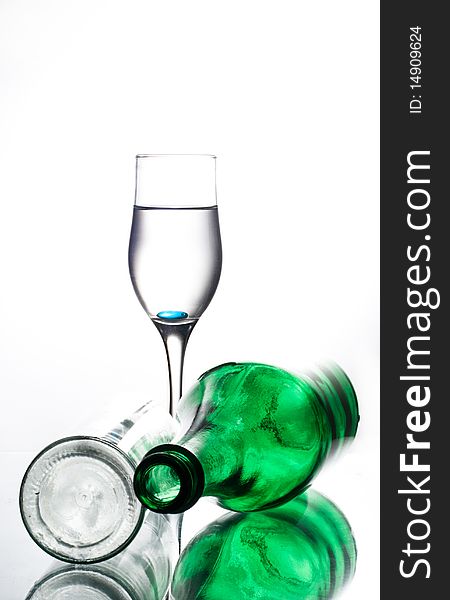 Green bottle and two glasses on glass table water