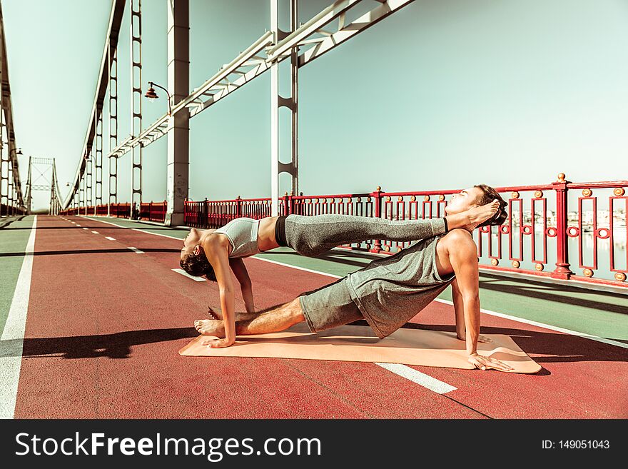 Harmony with nature. Couple of young yogis doing their stretching workout outdoors in fine summer weather. Harmony with nature. Couple of young yogis doing their stretching workout outdoors in fine summer weather
