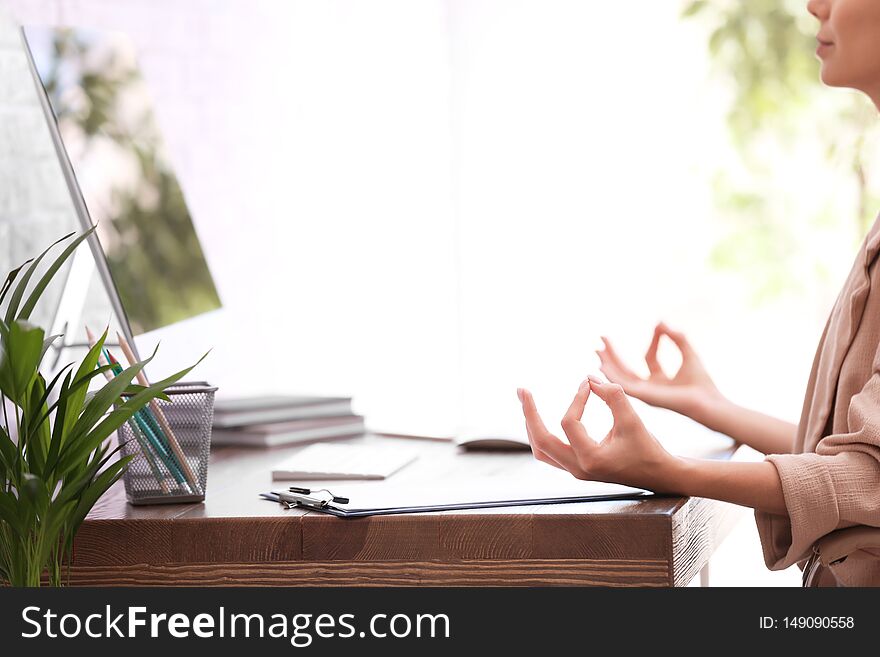 Businesswoman meditating at workplace, closeup with space for text