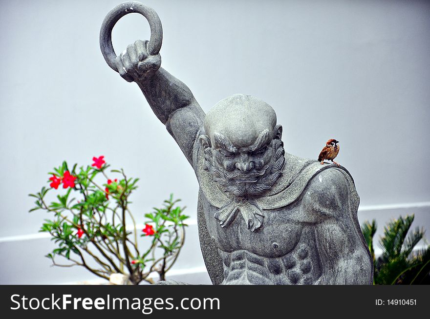 Fierce Chinese warrior statue and a little bird. Fierce Chinese warrior statue and a little bird