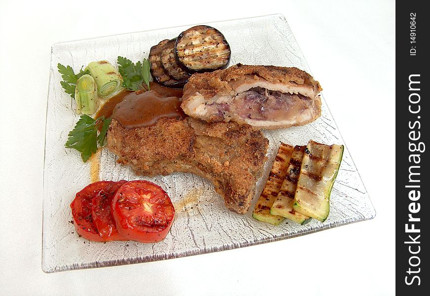 The meat loaf with mushrooms with pices of tomatoes, eggplant and zucchini grilled on the square glass plate. The meat loaf with mushrooms with pices of tomatoes, eggplant and zucchini grilled on the square glass plate.